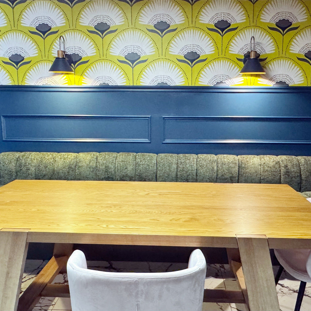 Wooden table with chairs against a blue wall with decorative yellow and white pattern