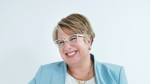 Woman wearing glasses and a light blue jacket on a white background