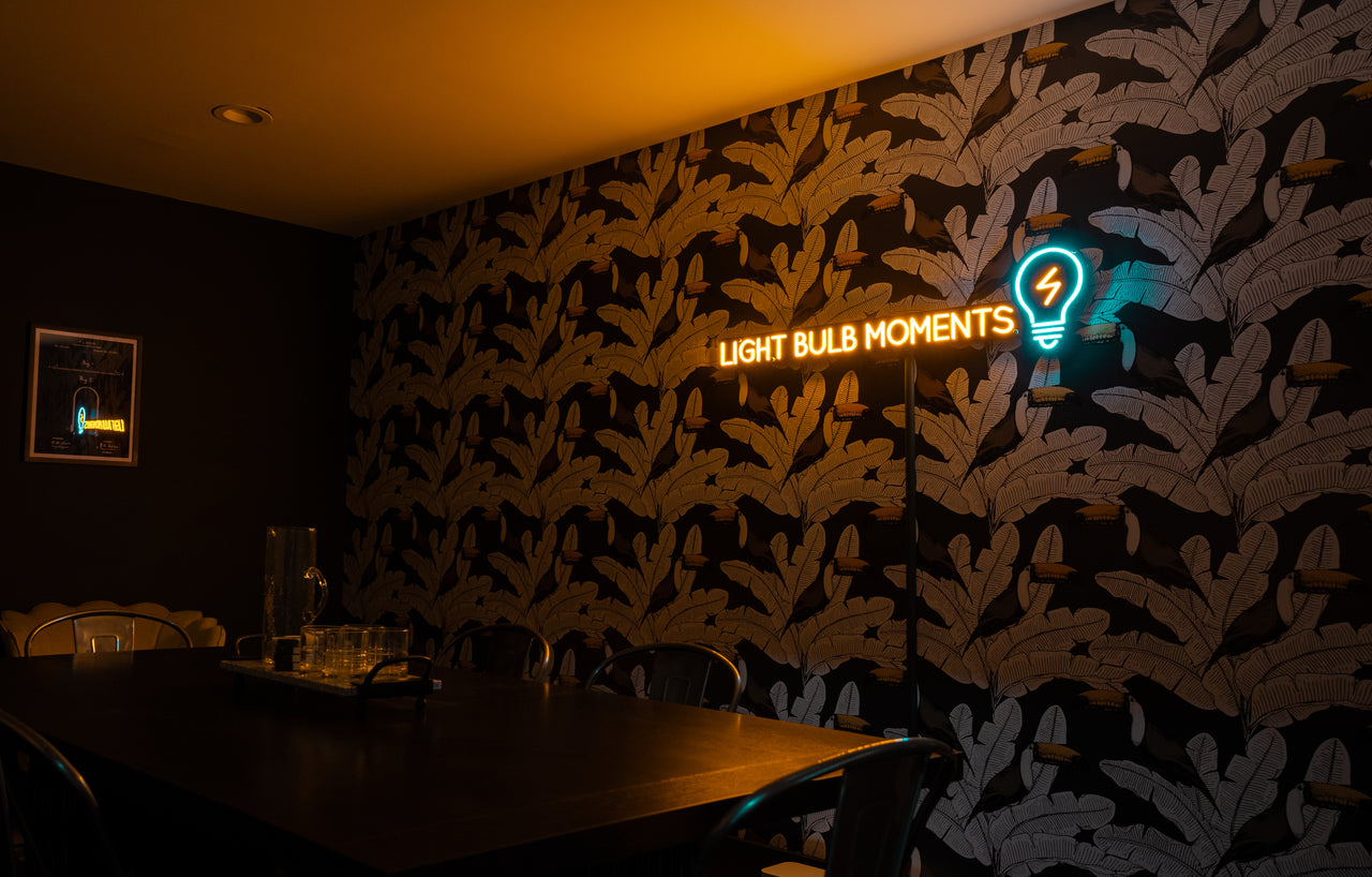 Neon light the says "Lightbulb moments" on wallpaper 