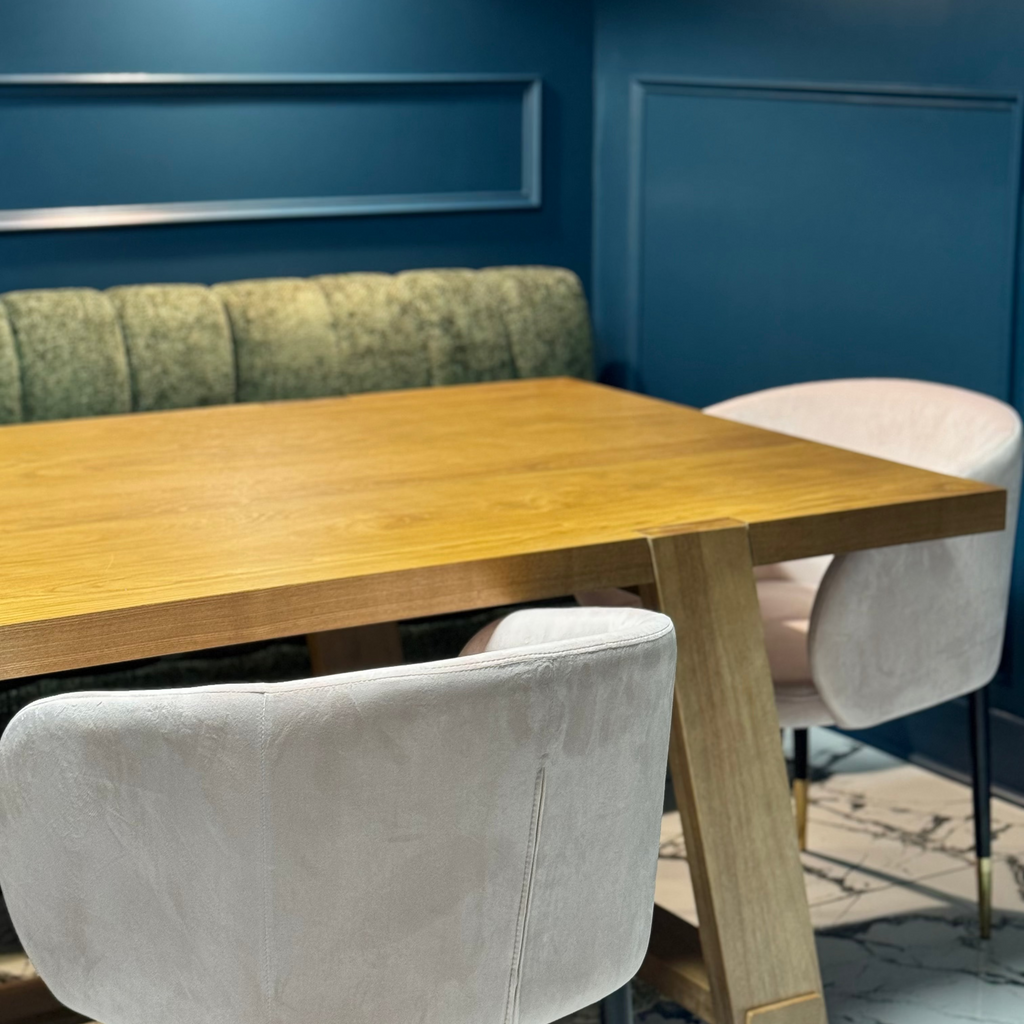 Dining area with wooden table and pink chairs against a blue wall.