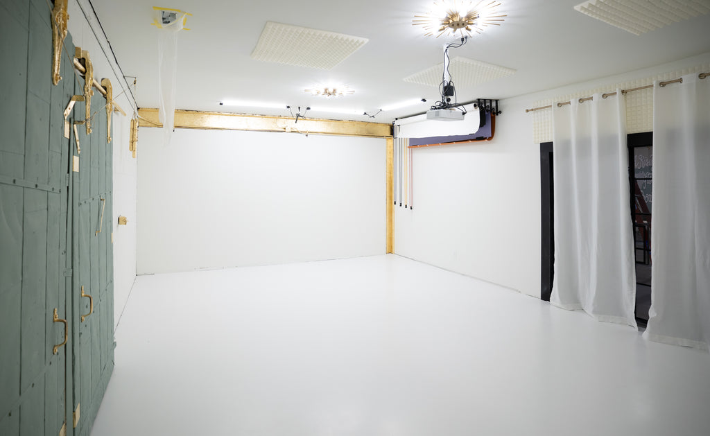Photography studio with white and gold walls, equipped with lighting and a projector