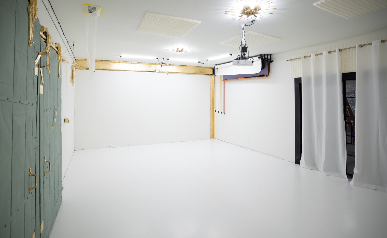 Photography studio with white and gold walls, equipped with lighting and a projector