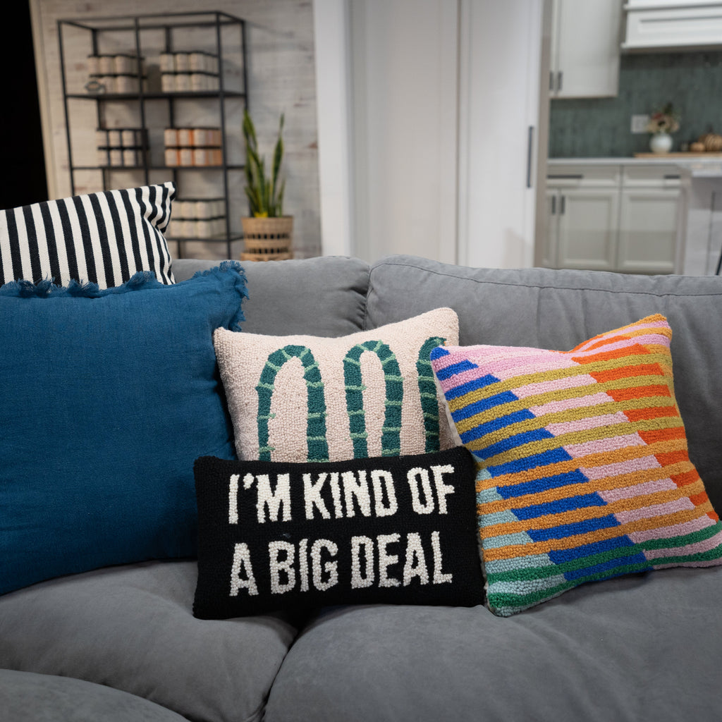 Gray sofa with colorful pillows including a black one with text in a living room setting.