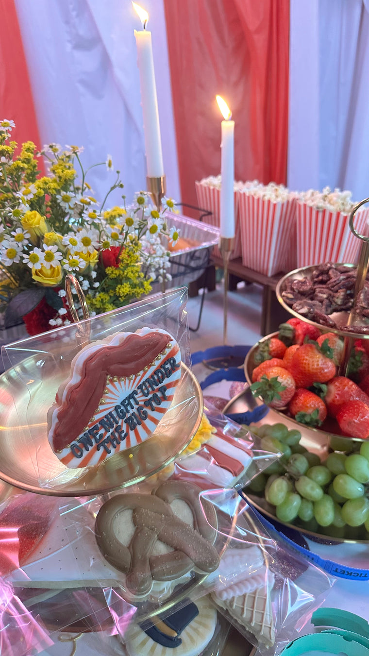 Decorative table with cookies, fruits, and flowers against a red curtain background