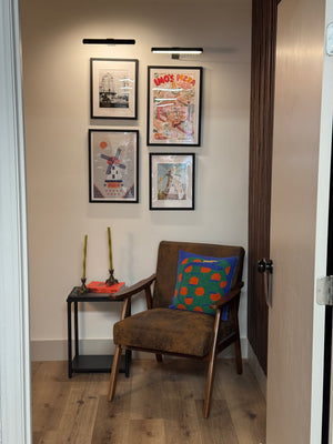 A doorway leading into a room with a brown chair and St. Louis artwork on the walls