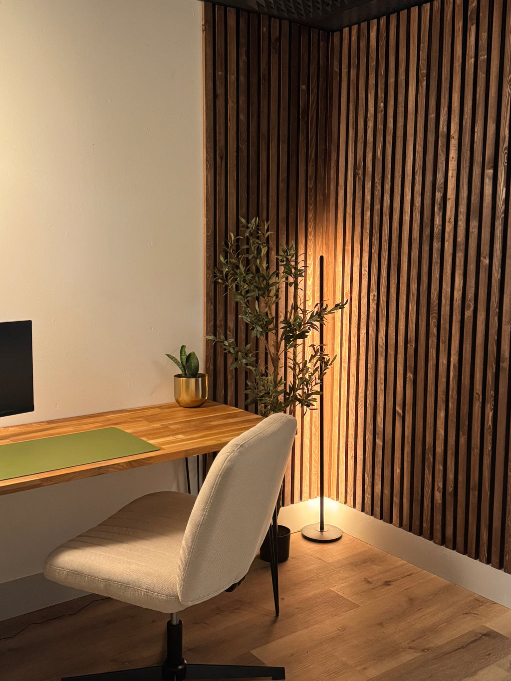 A modern room with wooden accent walls, a desk, chair, and a floor lamp, designed for content creation activities like podcast recording or video filming.