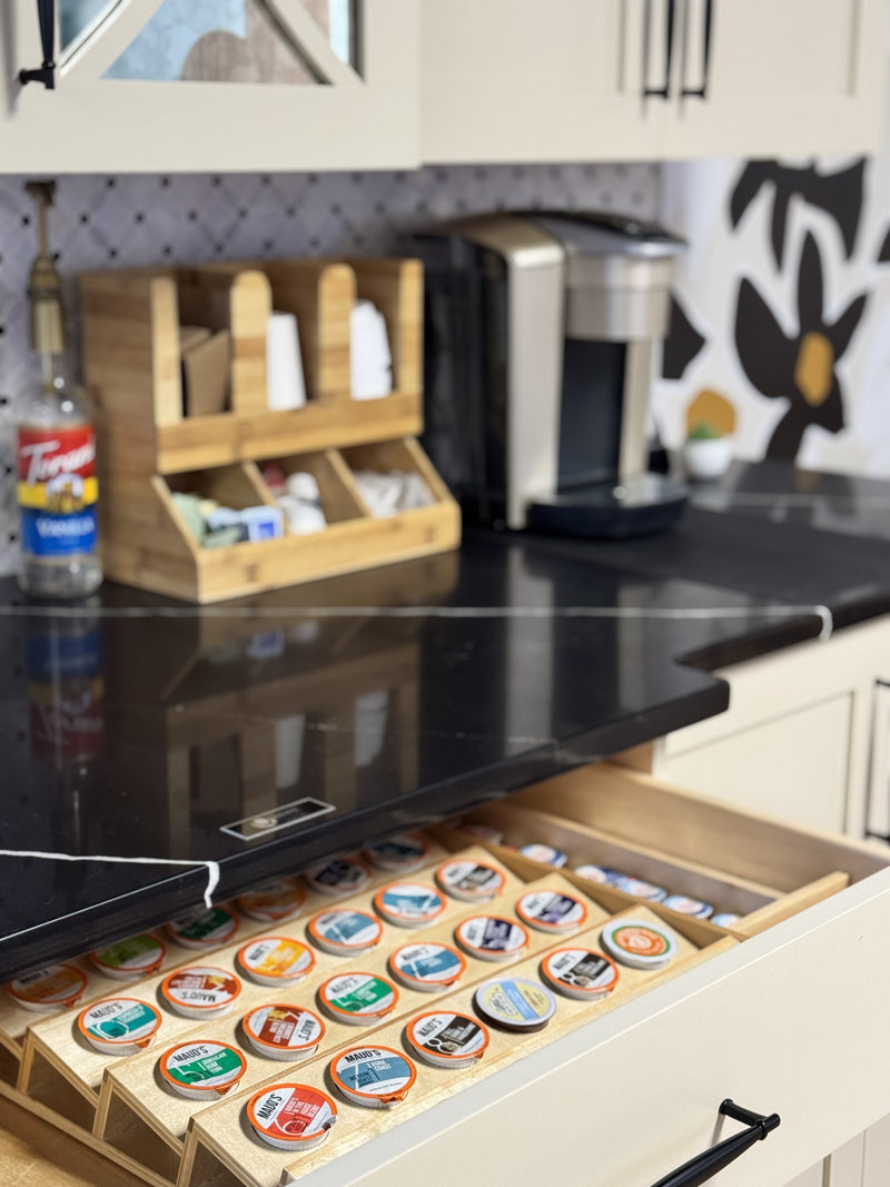 Kitchen counter with a drawer full of coffee pods and a coffee maker.