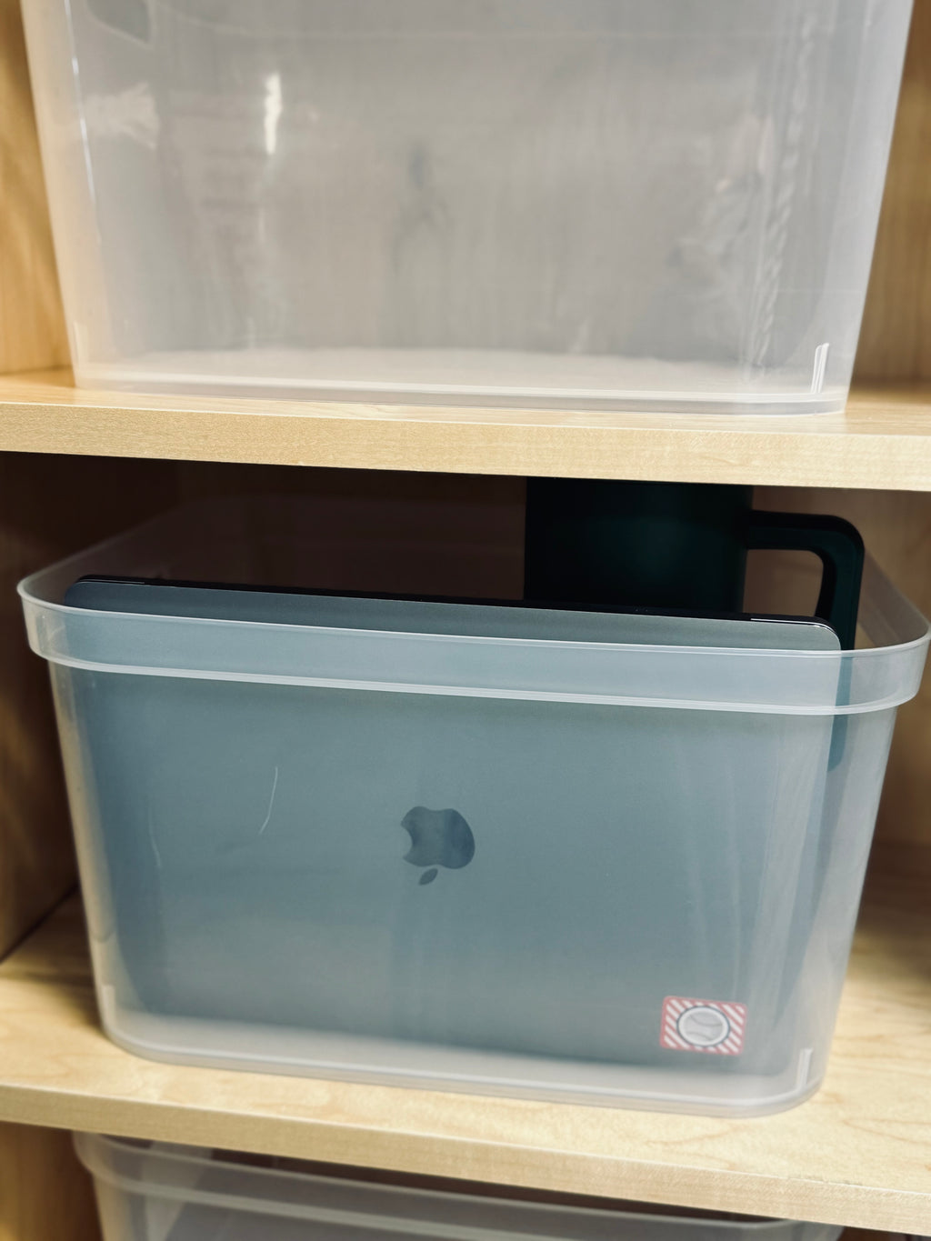 Clear storage bins with Apple logo on a wooden shelf