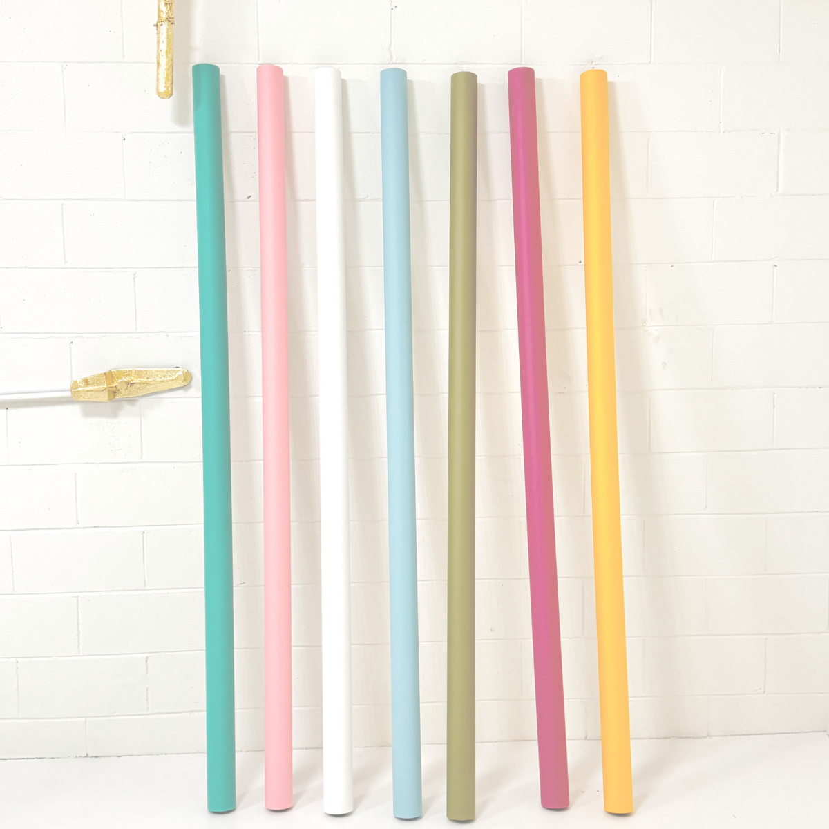Set of colorful rolls of paper on a white brick wall.